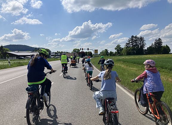 Platz da für Kinder auf dem Rad Die Fahrraddemo unterwegs auf der Landesstraße, die Kamera fährt hinter mehreren Kindern und einem Erwachsenen