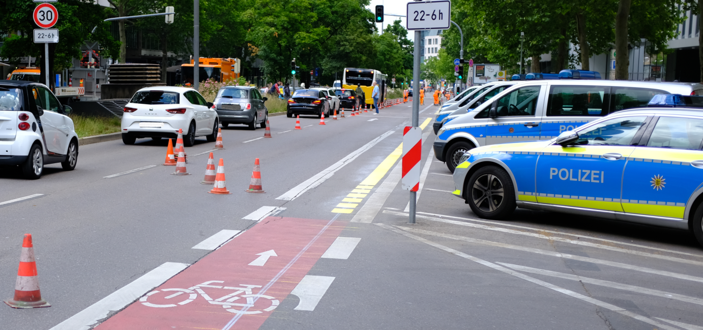 Ein schmaler Radfahrstreifen an einer viel befahrenen Straße. Die Verkehrssituation scheint wenig übersichtlich zu sein. 