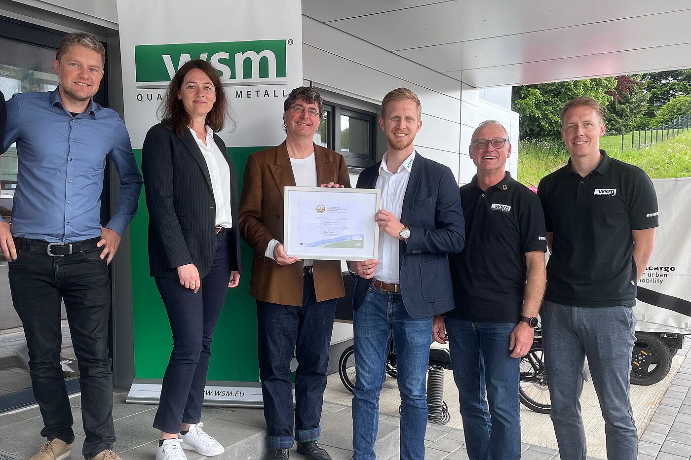 240522_ffa_presse_WSM_01 Zertifikatsübergabe (Gold) an WSM – Walter Solbach Metallbau GmbH, Waldbröl am 22. Mai 2024 v.l. Rudolf Bergen (Mobilitäts- und Klimaschutz-Manager Stadt Waldbröl), Larissa Weber (Bürgermeisterin Stadt Waldbröl), Andreas K. Bittner (ADFC / "Fahrradfreundlicher Arbeitgeber"), Christoph Solbach (Geschäftsführer WSM), Andreas Hombach (Betrieblicher Mobilitätsmanager, IHK, WSM) und Rico Henseleit (Radverkehrskoordinator, WSM).